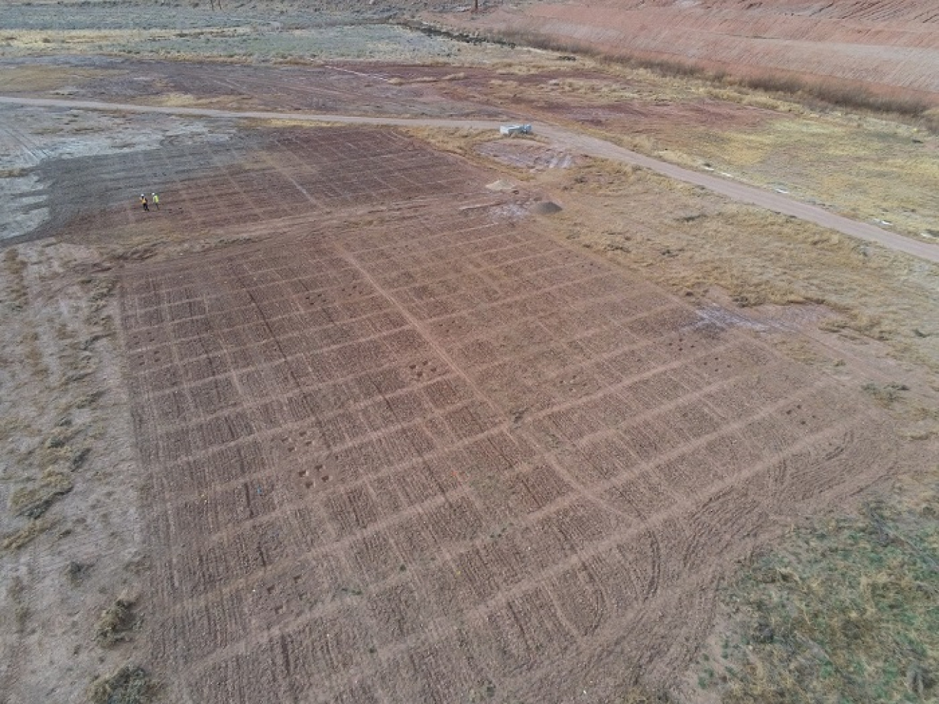 Moab Uranium Mill Tailings Remedial Action Project Environment Technician Luke Mattson and Project Engineer Chris Pulskamp, shown in the upper left corner of the photo, examine revegetation test plots after the land was prepped for planting.