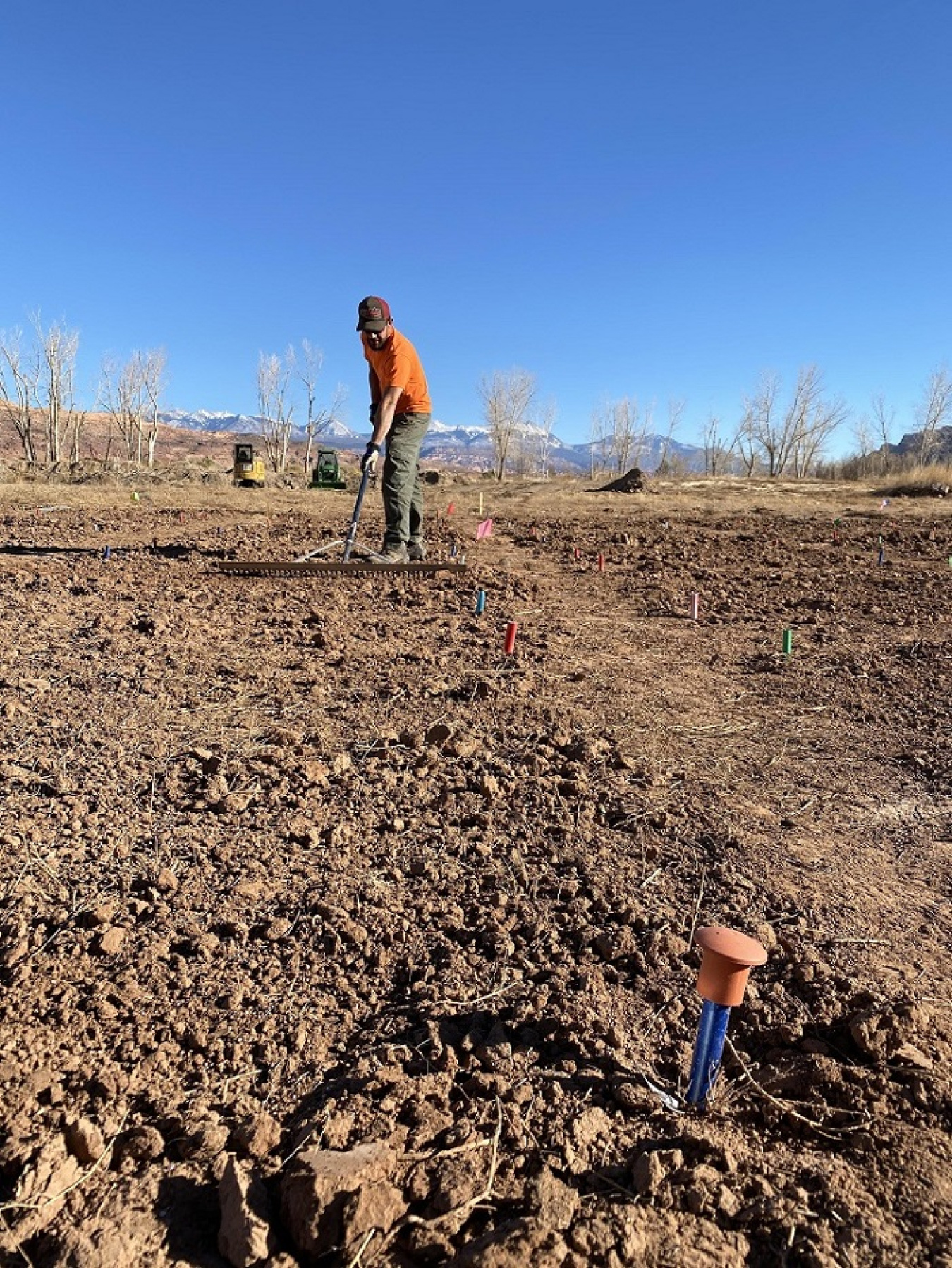 Revegetation Technician Erik Parker rakes seed into a research plot at the Moab Uranium Mill Tailings Remedial Action Project.