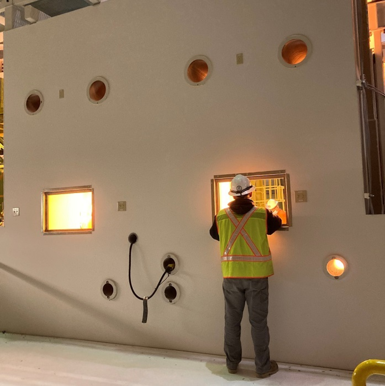 Hanford Site electrician Fonzie Lopez looks inside a simulated radiation containment chamber called a hot cell during construction of a mock-up to prepare workers to safely move nearly 2,000 capsules of highly radioactive cesium and strontium.