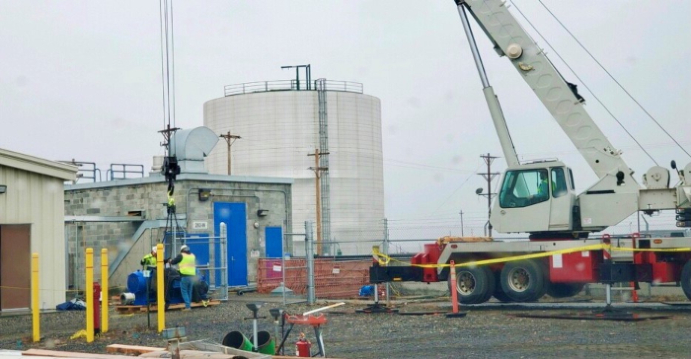 Workers lift a new pump into a reservoir on the Hanford Site as part of planned upgrades to the site’s untreated water system.