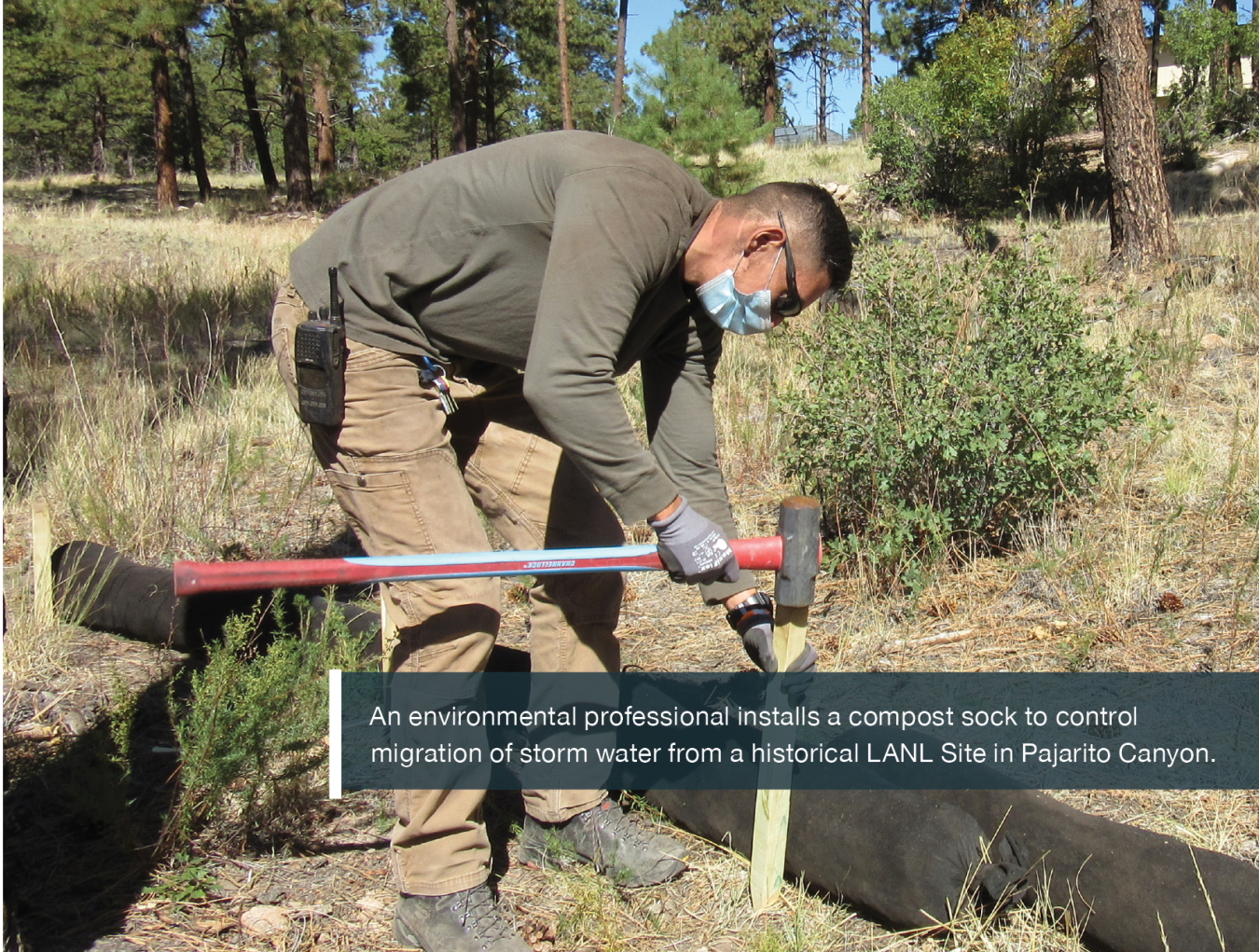 An environmental professional installs a compost sock to control migration of storm water from a historical LANL Site in Pajarito Canyon.