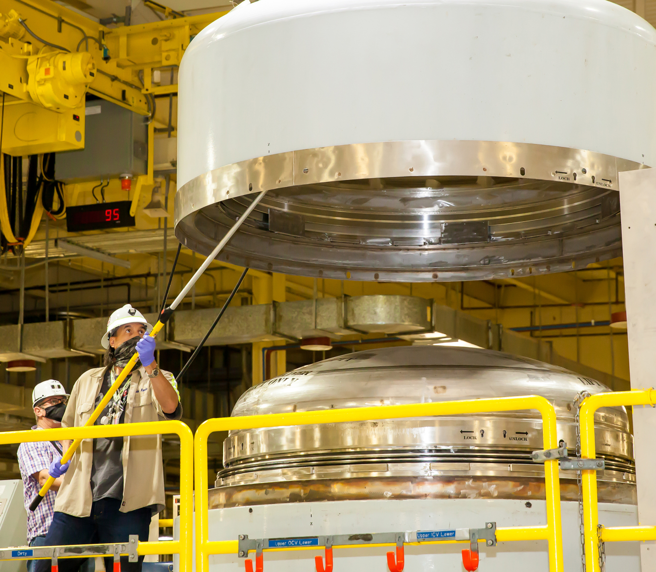 A radiological worker surveys the inside of a TRUPACT-II containment lid during waste handling operations at the Waste Isolation Pilot Plant in New Mexico.
