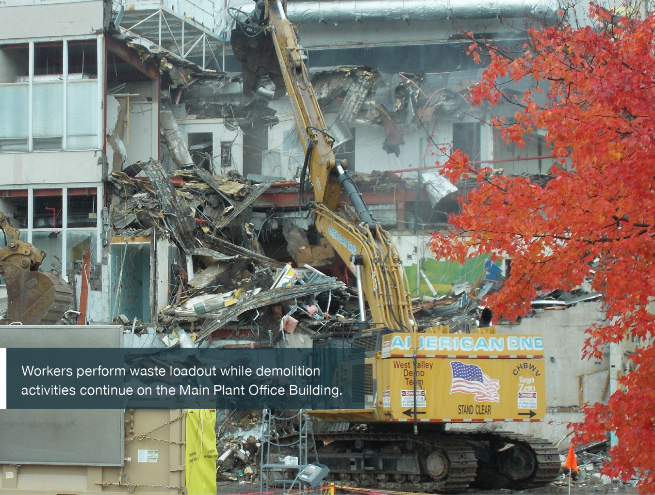 Workers perform waste loadout while demolition activities continue on the Main Plant Office Building.