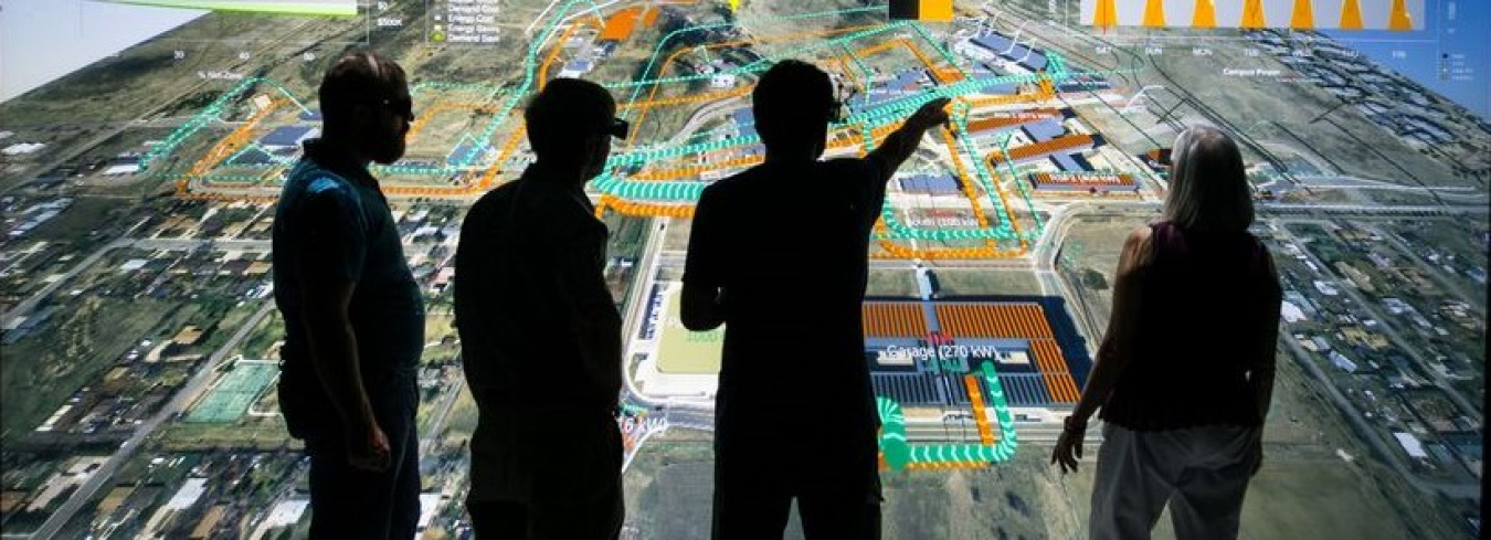 Silhouettes of four people in front of a visualization.