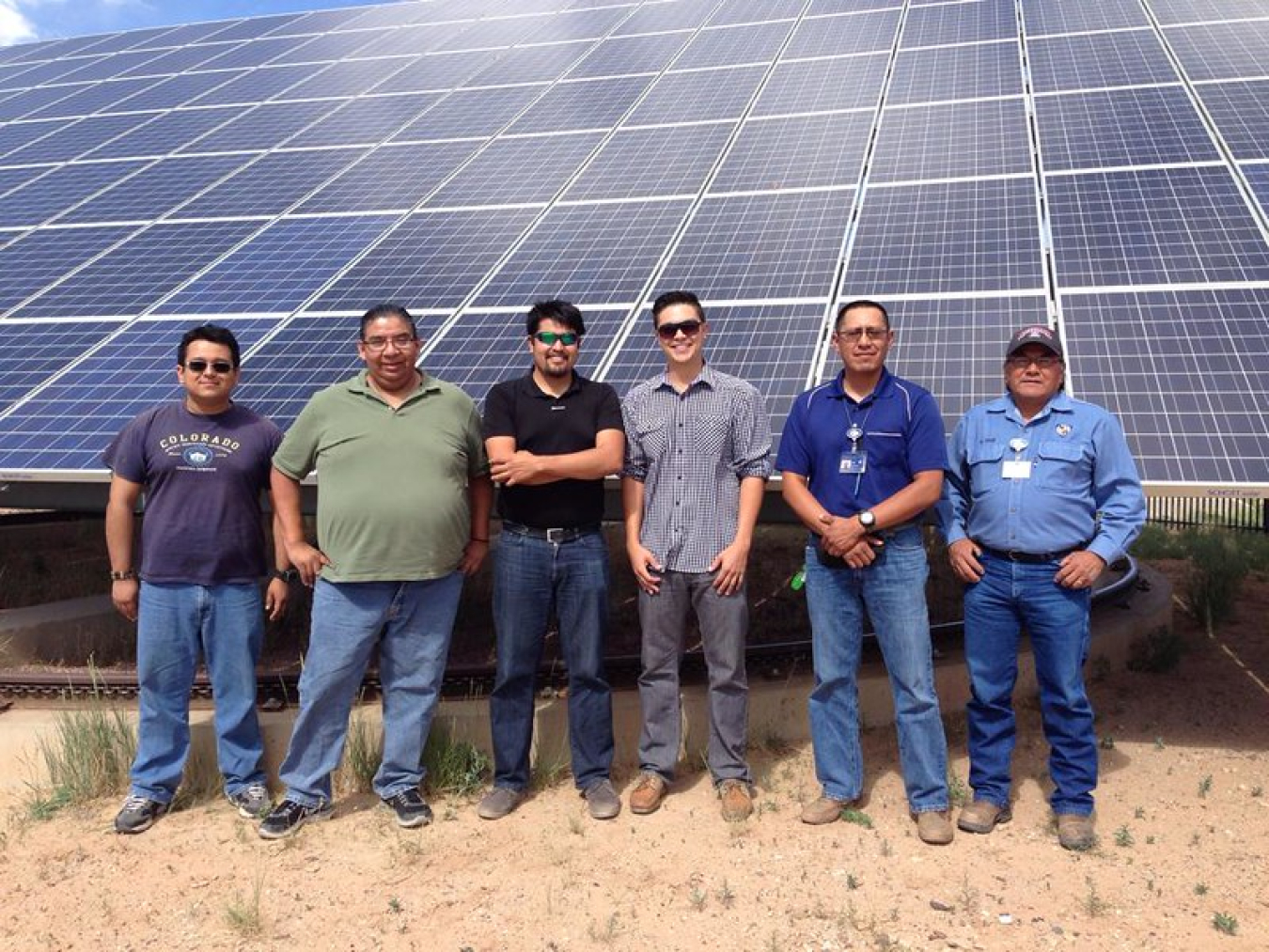 Interns stand in front of solar panel.