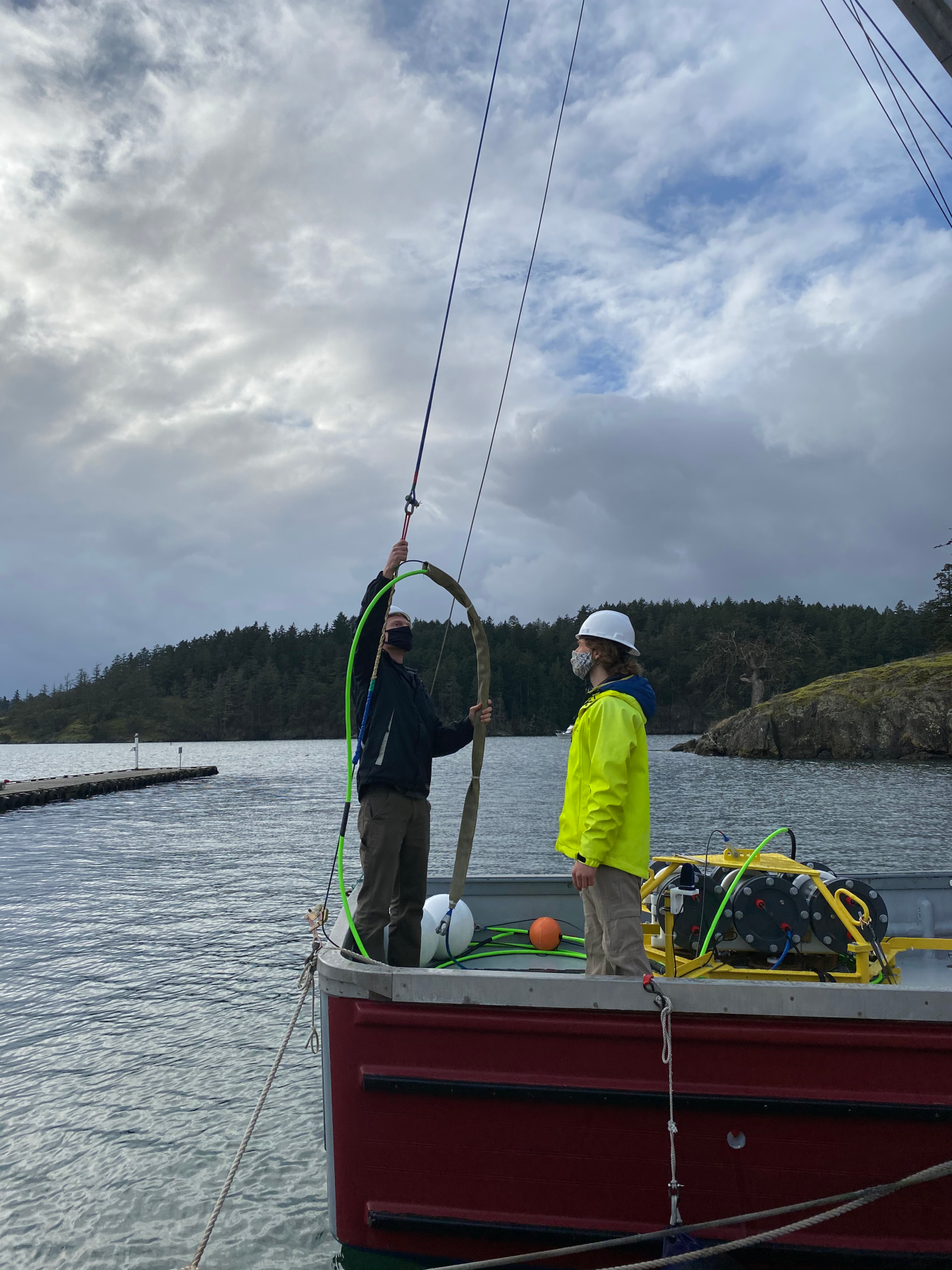 Photo of two men on a boat preparing an acoustic buoy unit for deployment.