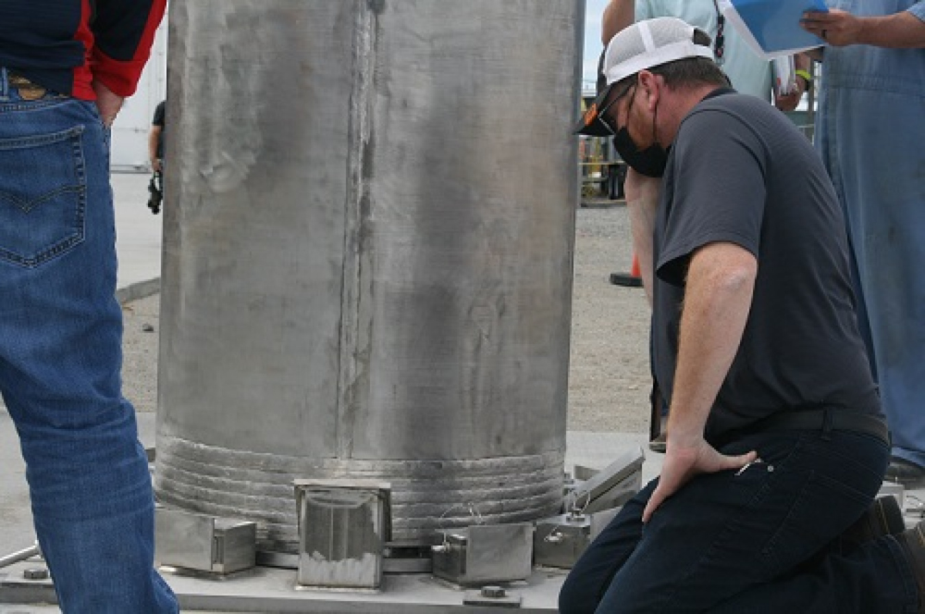 Washington River Protection Solutions engineer Blake Chamberlain inspects the connection between an ion-exchange column and the bolts holding it in place on a concrete storage pad.