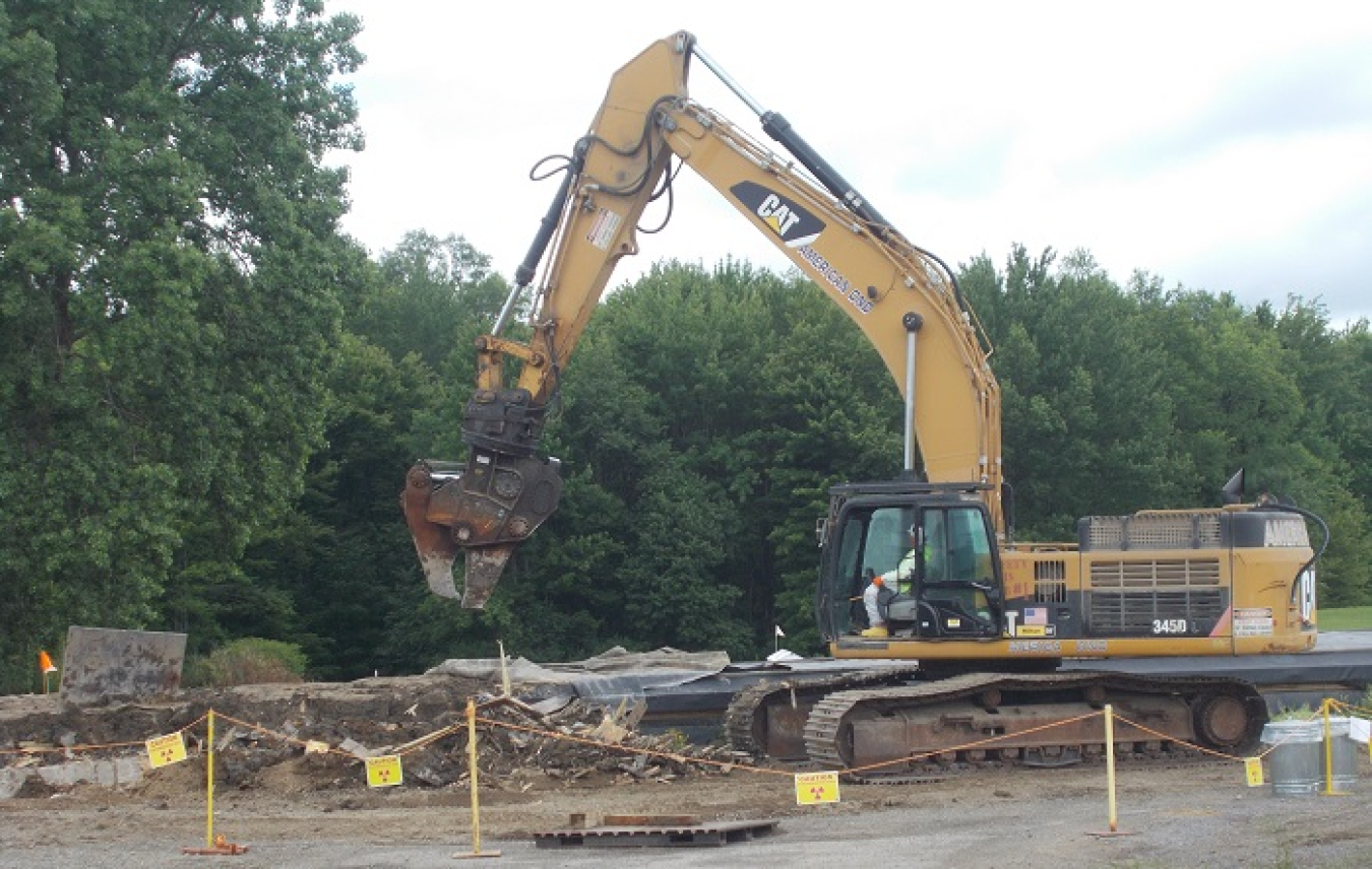 Workers use an excavator to remove soil that had been excavated for the installation of a unique groundwater treatment system at the West Valley Demonstration Project years ago. The soil and a structure used to store the soil will be shipped offsite by rail this month.