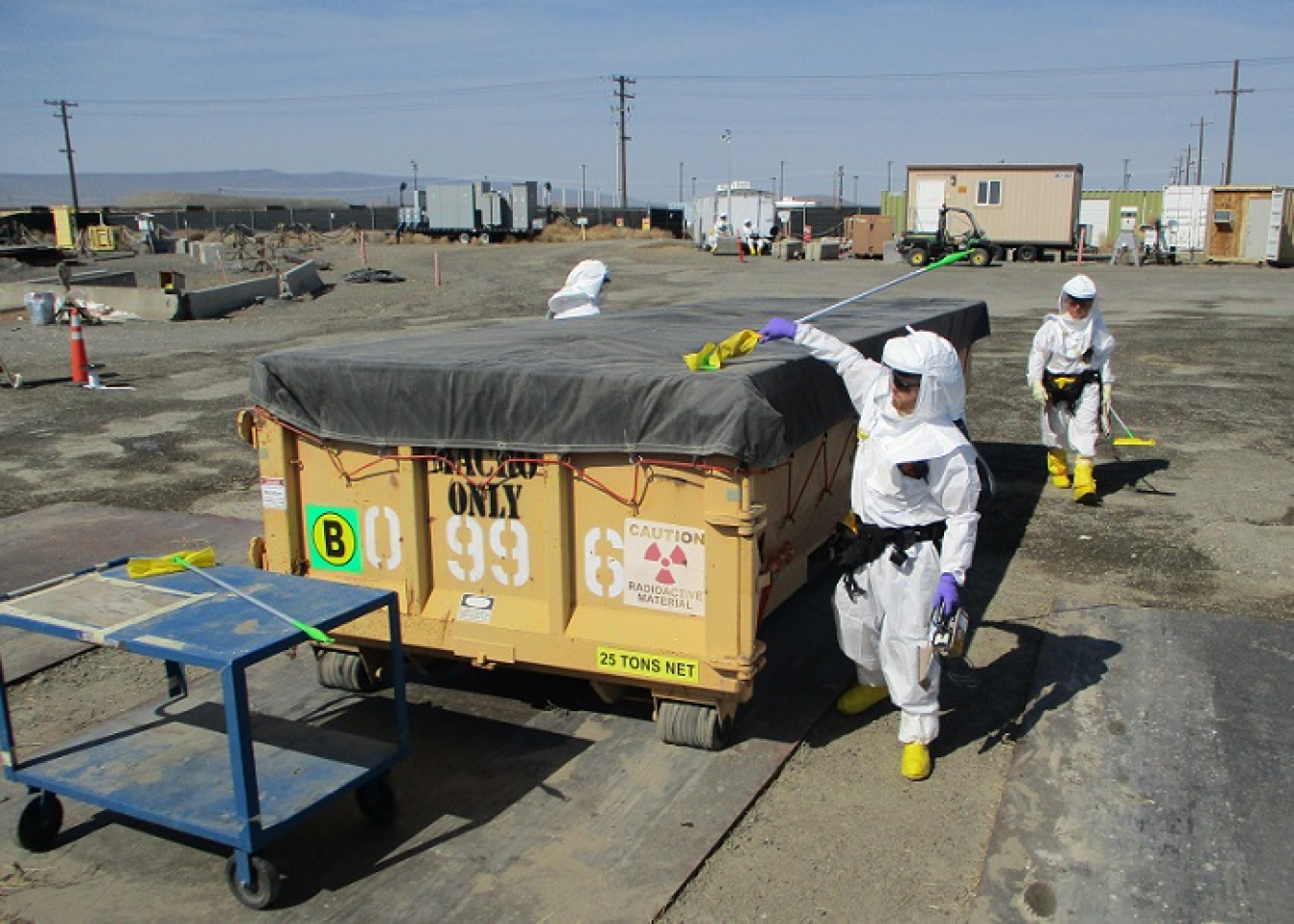 A worker with EM contractor Central Plateau Cleanup Company surveys a loaded waste container at the site of the former Plutonium Finishing Plant to ensure it is safe for transfer to Hanford’s on-site disposal facility.