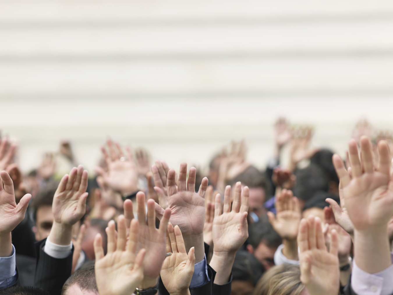 Closeup of business crowd raising hands