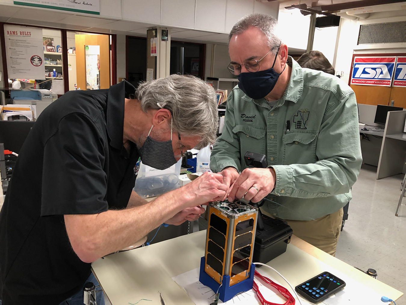 ORNL's Peter Thornton and volunteer technical mentor David Andrews work together to prepare RamSat during the final assembly stage. 