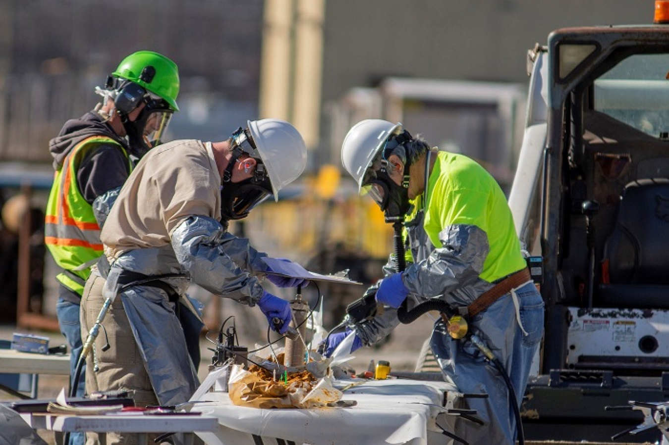 From left, geologist Mitch Stewart, radiological control technician Dan Lang, and geologist Ken Davis examine soil cores prior to collecting samples during a study of groundwater contamination beneath the C-400 Cleaning Building. 