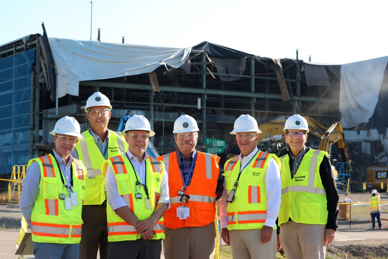 From left, EM Acting Chief of Staff Erik Olds, Portsmouth/Paducah Project Office (PPPO) Deputy Manager Joel Bradburne, EM Acting Assistant Secretary William “Ike” White, PPPO Manager Robert Edwards, DOE Associate Under Secretary for Environment, Health, Safety and Security Matthew Moury, and Portsmouth Site Lead Jeff Bettinger stand in front of the X-326 Process Building under demolition.