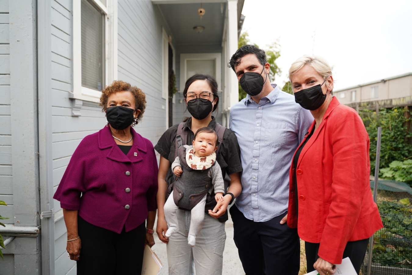 A group of people posing together and wearing masks.