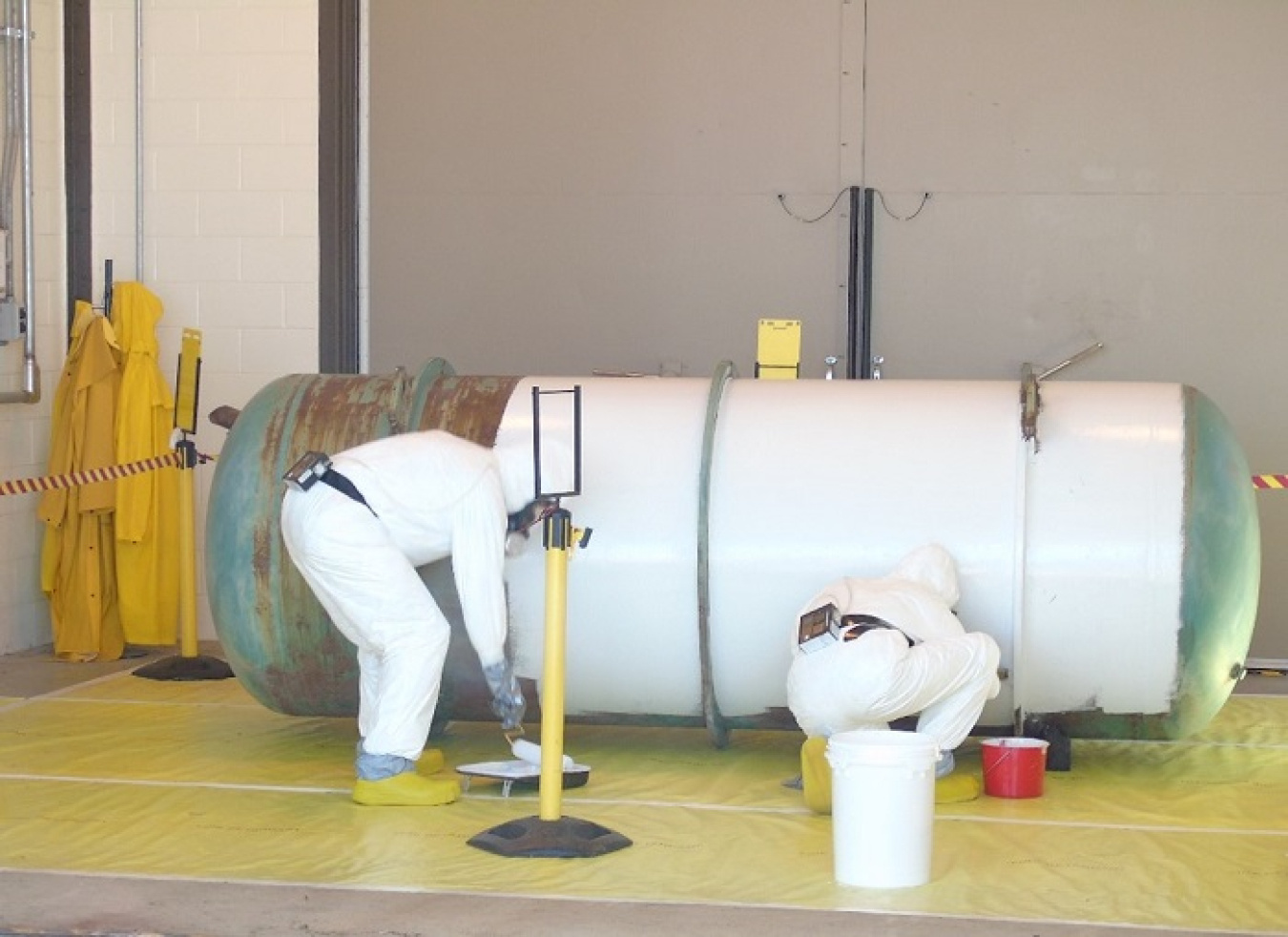Mid-America Conversion Services operator-technicians Pete Bowen, left, and Erica Stanley paint a cylinder with epoxy for contamination control.
