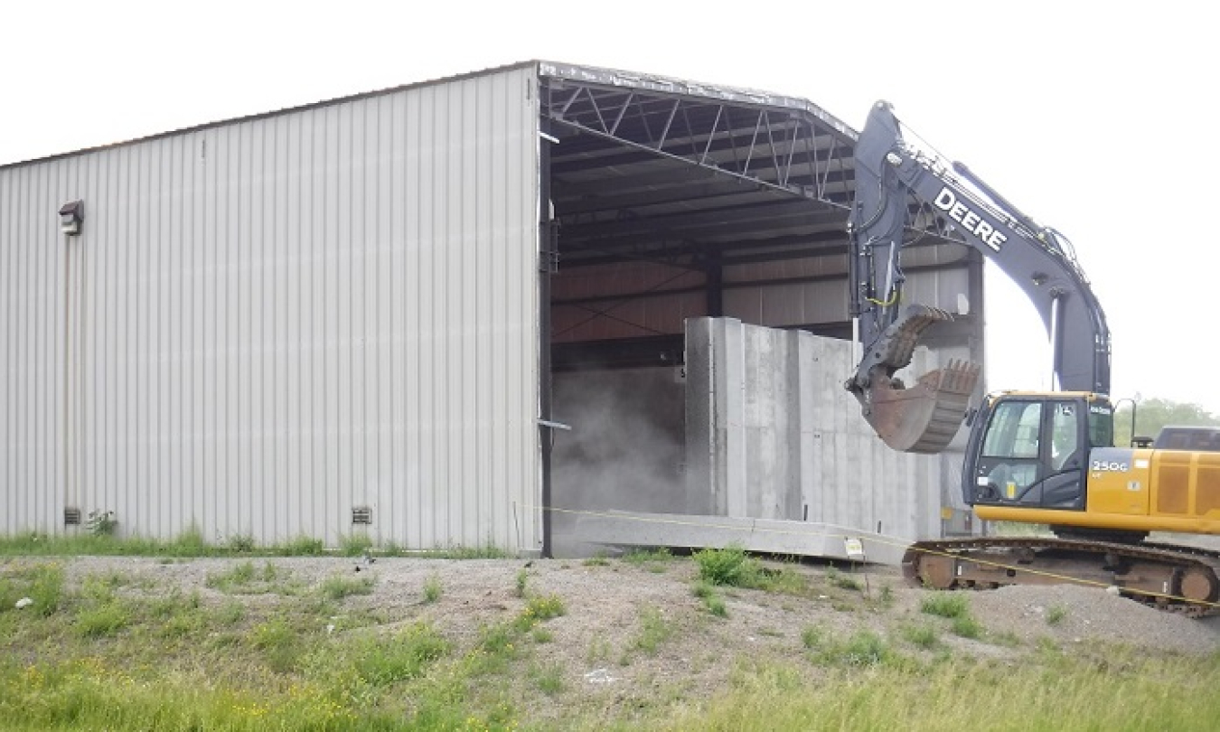 Workers at the West Valley Demonstration Project safely remove a section of a concrete shield wall as part of modifications to a former waste storage facility. A new rollup door will be installed in the opening. This facility will support waste operations during the future demolition of the Main Plant Process Building.