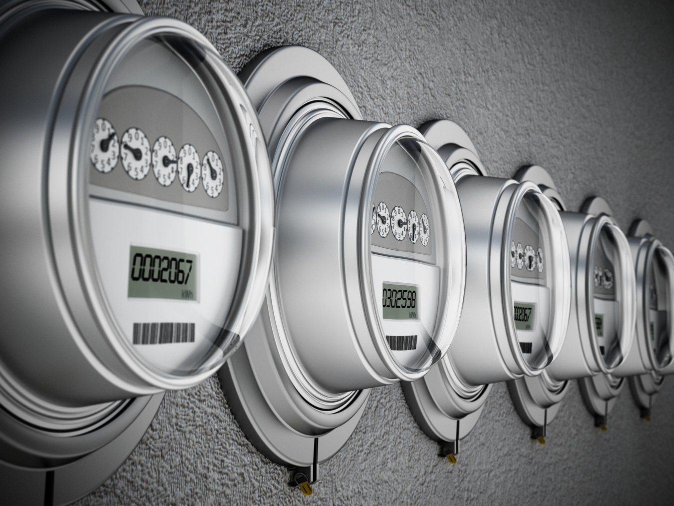 A row of shiny metal electric meters mounted to a wall.