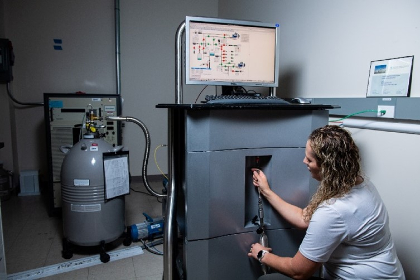 PNNL technician Jennifer Mendez attaches a gas cylinder to one of the systems used to measure samples collected at International Monitoring System stations.