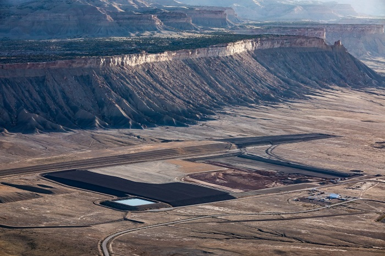 The Crescent Junction disposal cell looking north, toward Utah’s Book Cliffs. This photo depicts several phases of disposal cell construction, ranging from final cover on the left to newly excavated cell floor on the right.