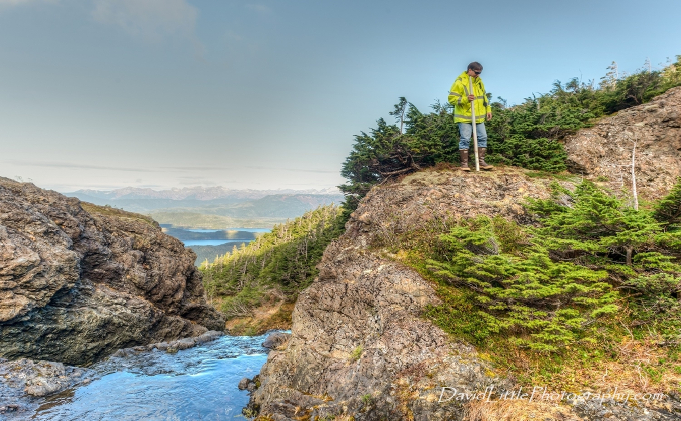 Person stands on a rock next to a creek.