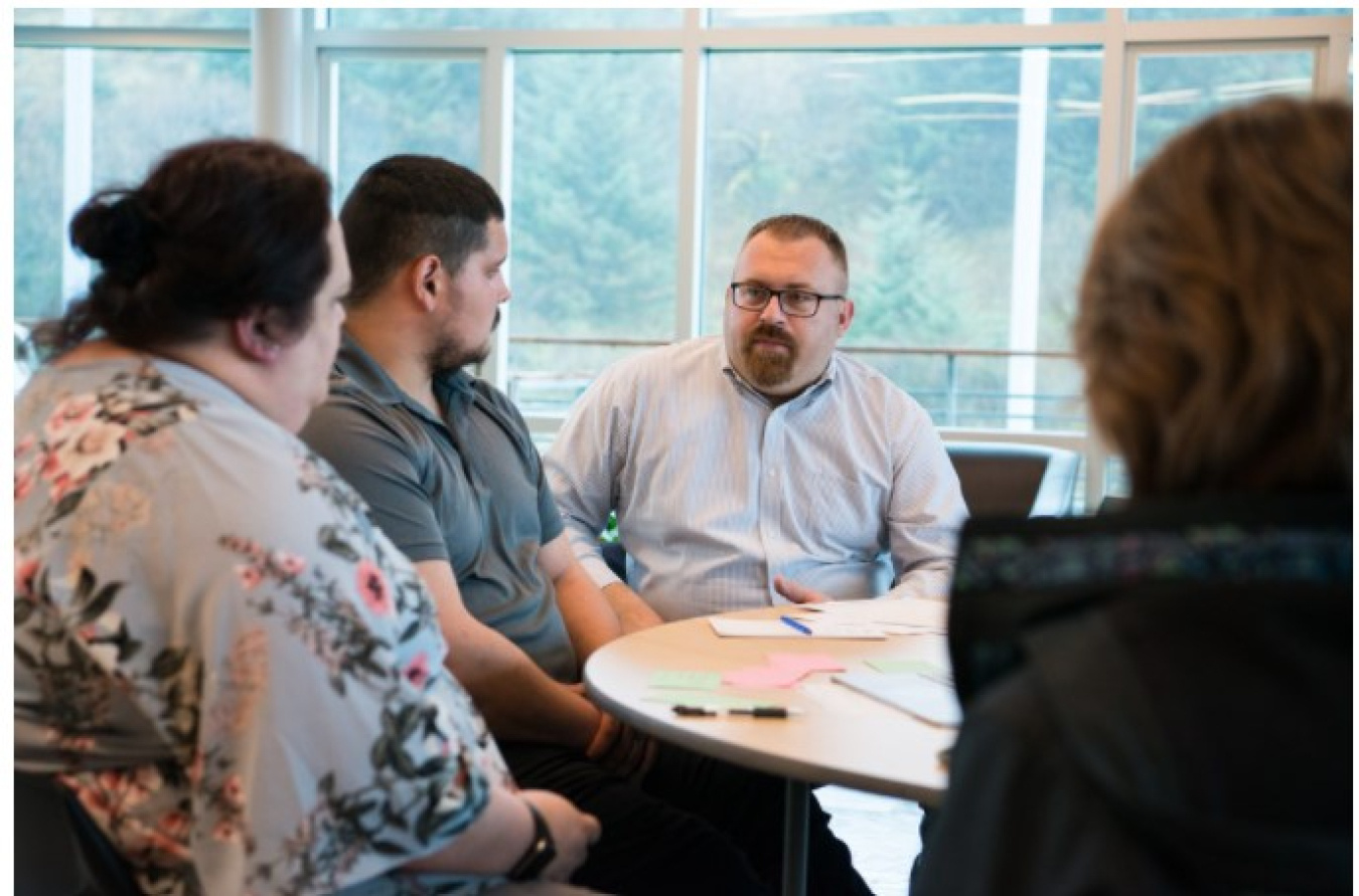 Givey Kochanowski speaks with participants at a table at an energy conference in Alaska.