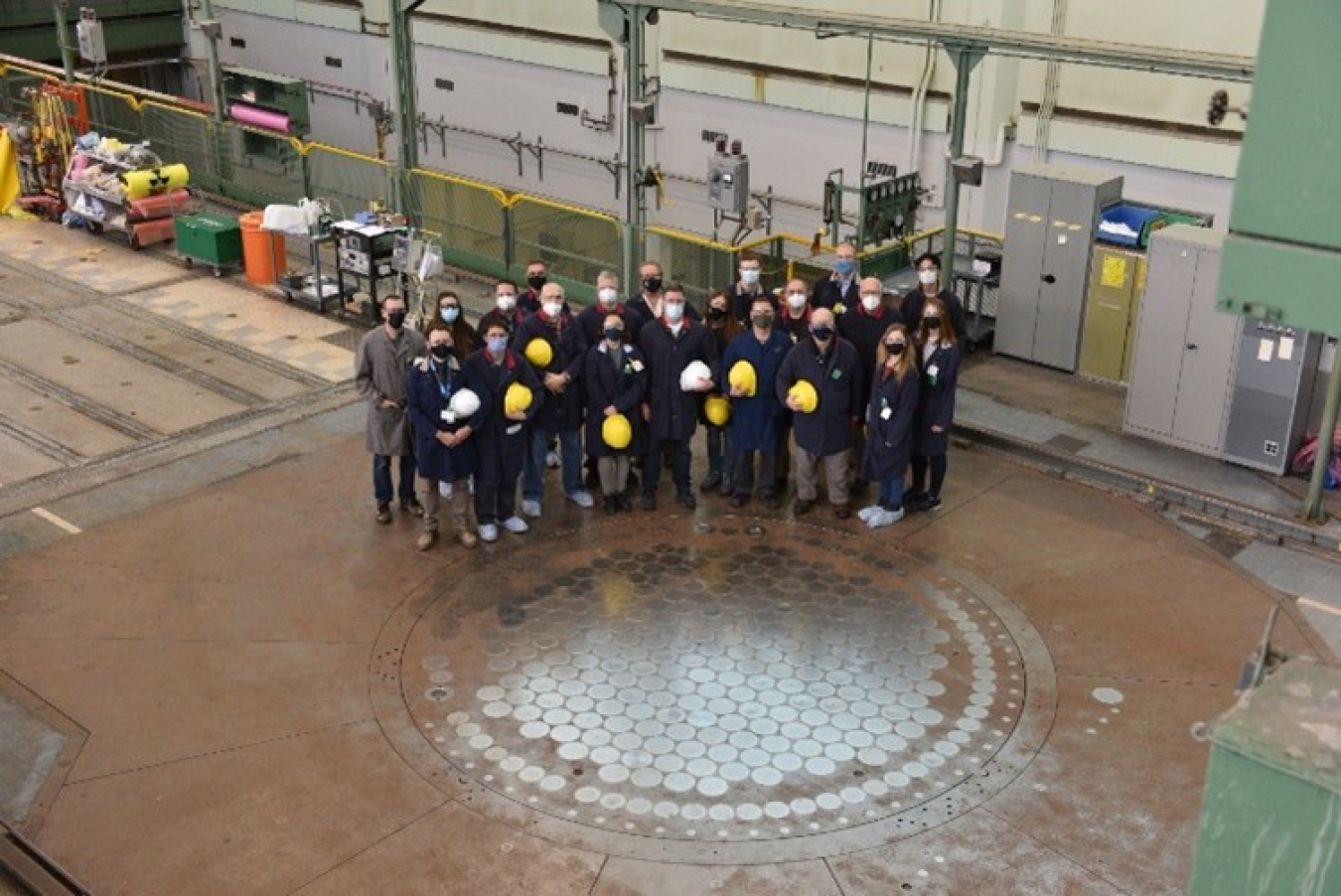 Team members from NNSA’s Plutonium Verification Team and Canadian Nuclear Laboratories stand next to the National Research Universal Reactor’s plate.