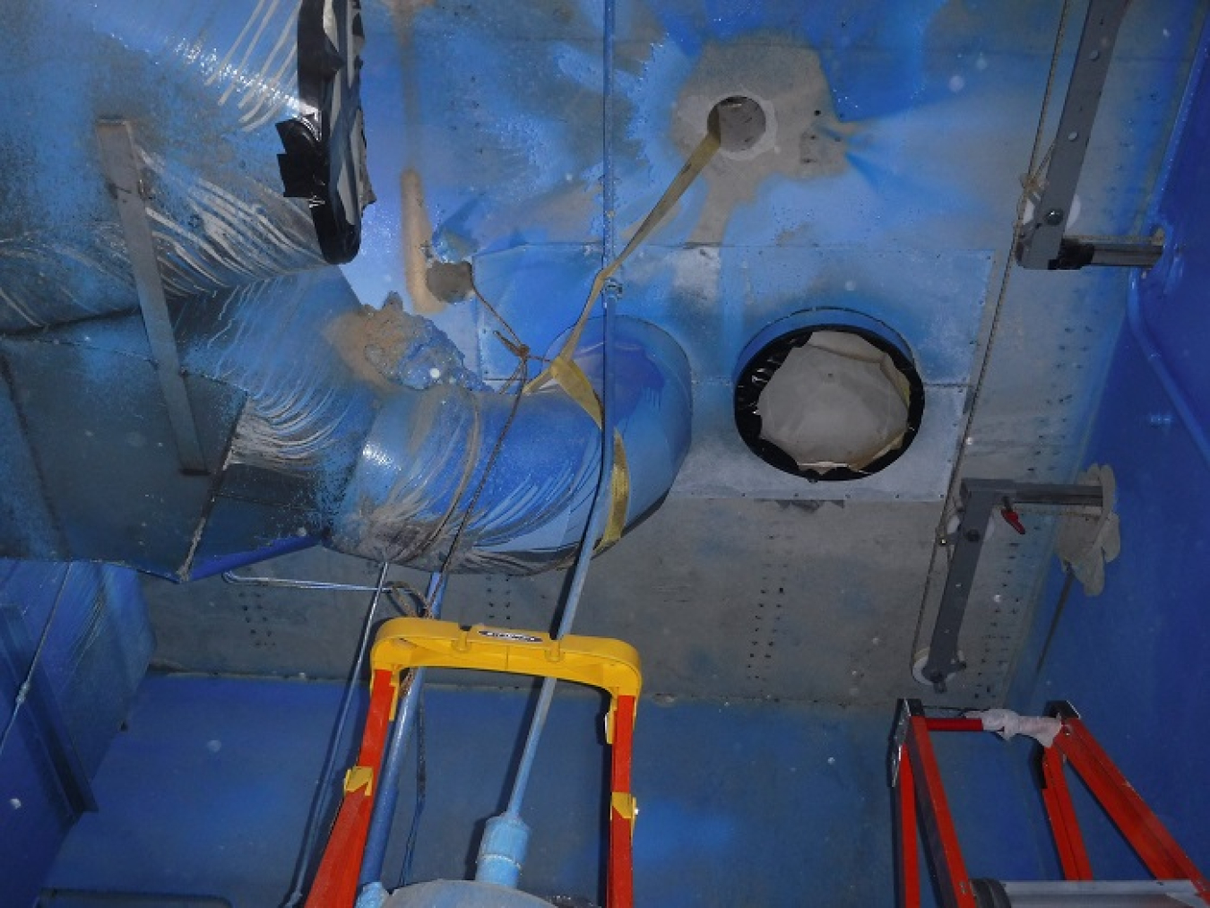 Workers at the West Valley Demonstration Project prepare a section of a ventilation duct to be cut inside the Vent Wash Room. The room had been used to support former reprocessing cells inside the Main Plant Process Building.
