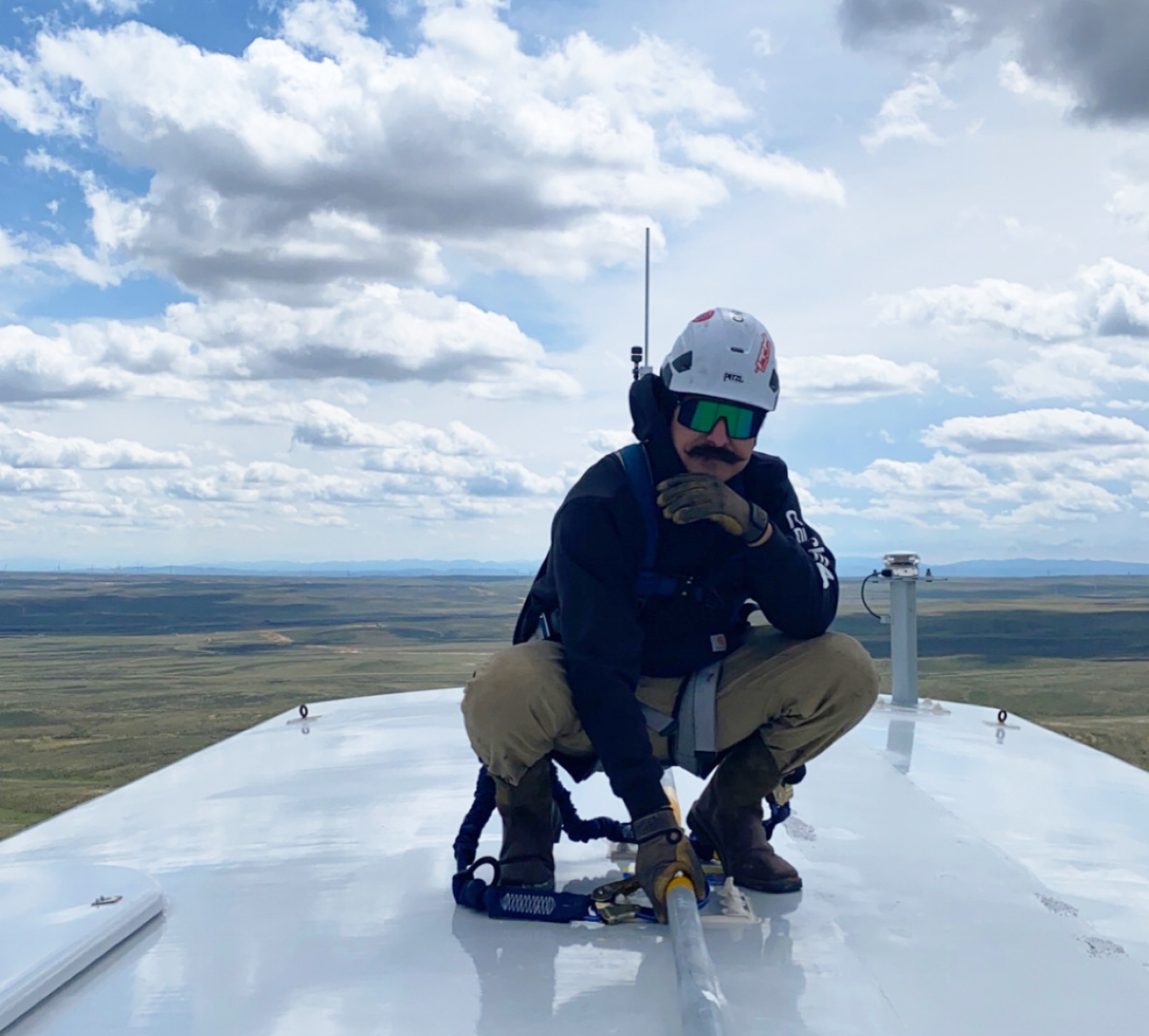 Michael Flores posing on top of a wind turbine.