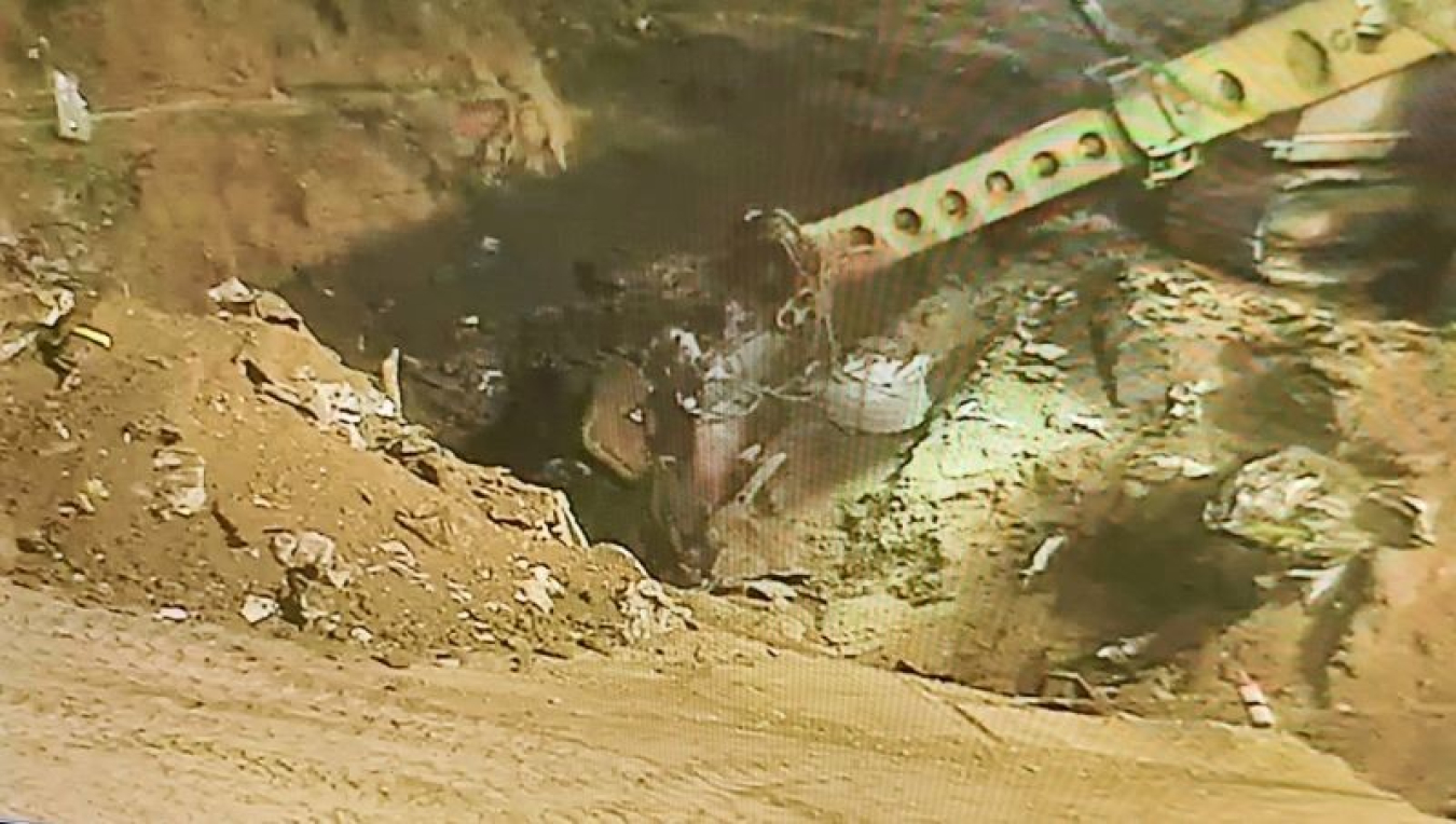 An extended-arm excavator retrieves the final waste from the Accelerated Retrieval Project IX facility 