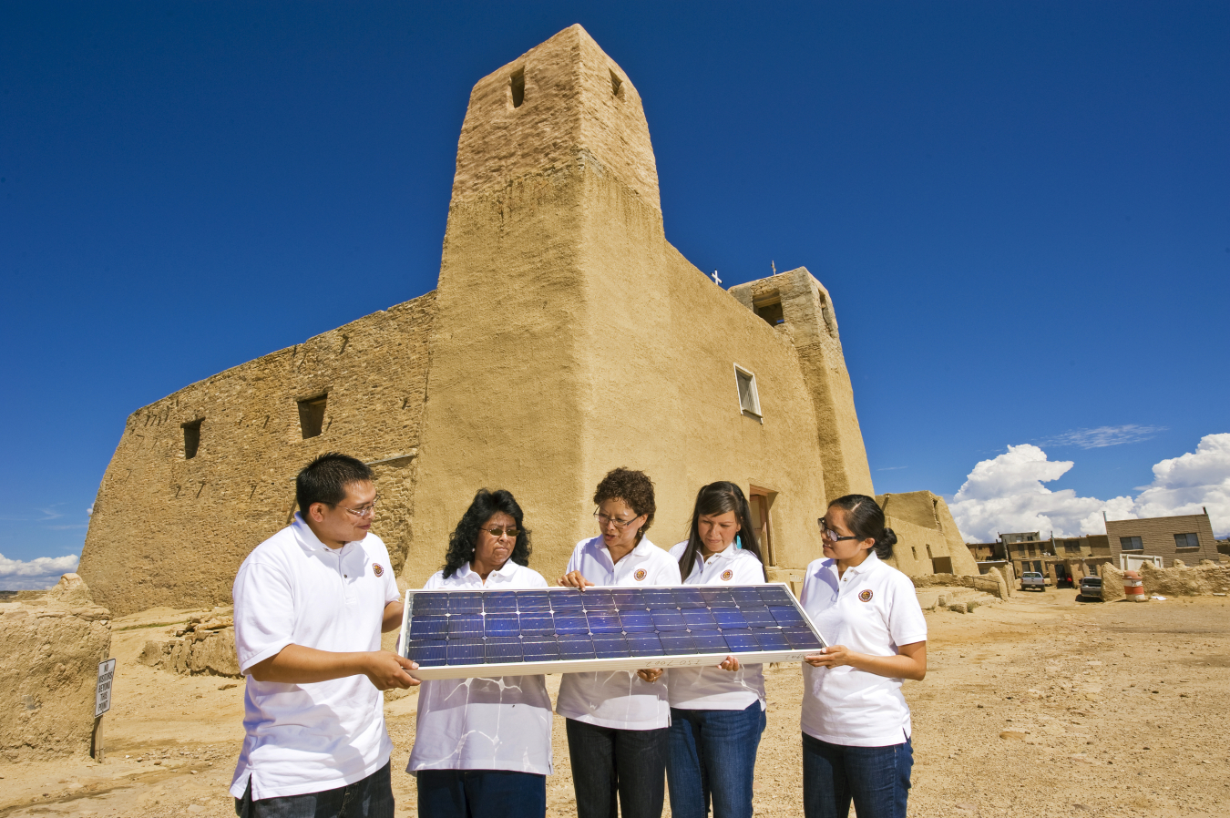 Group holding solar panel in desert