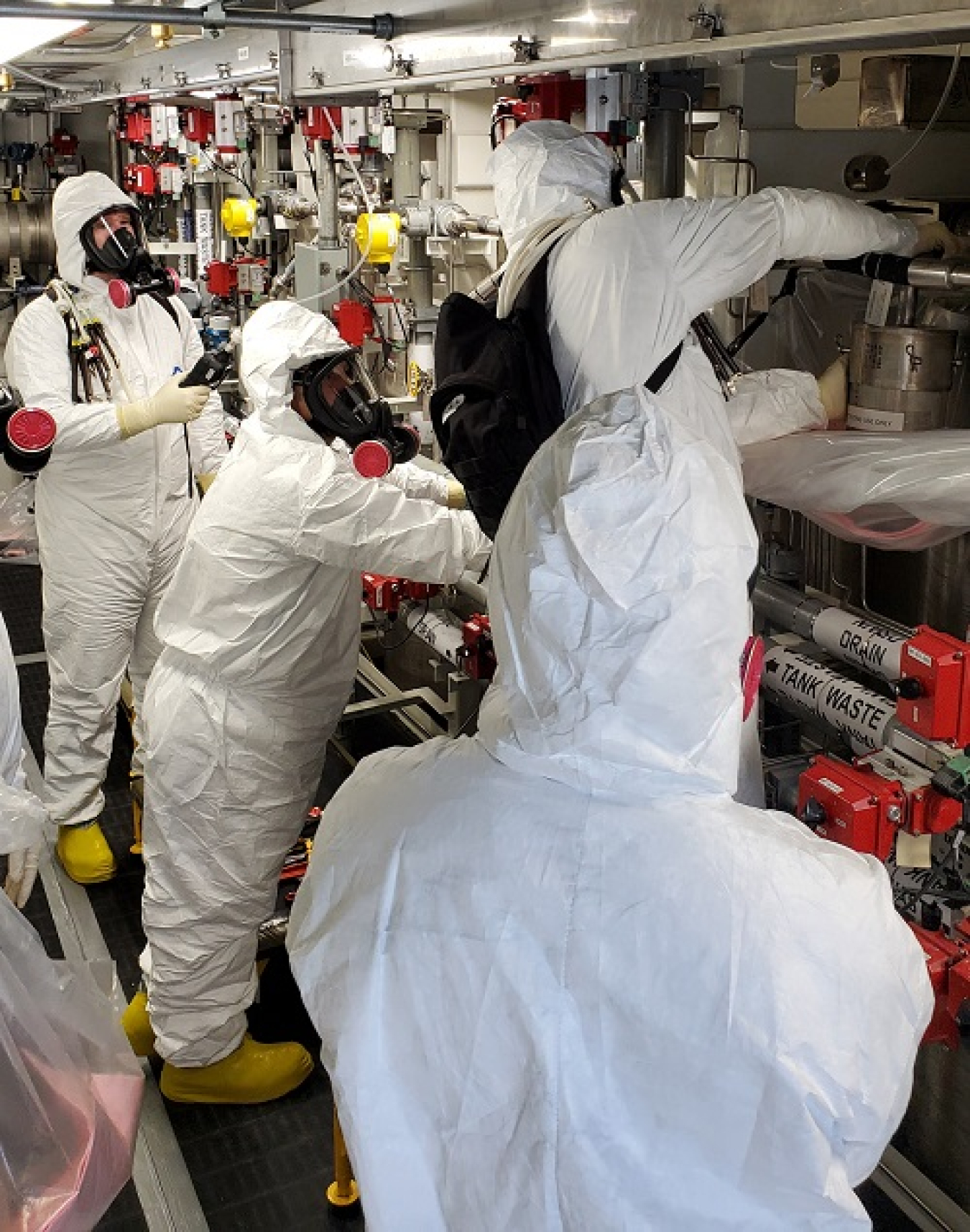 Washington River Protection Solutions workers in full protection gear worked inside the Tank-Side Cesium Removal System’s process enclosure to practice unhooking the hoses that connect the ion exchange columns.