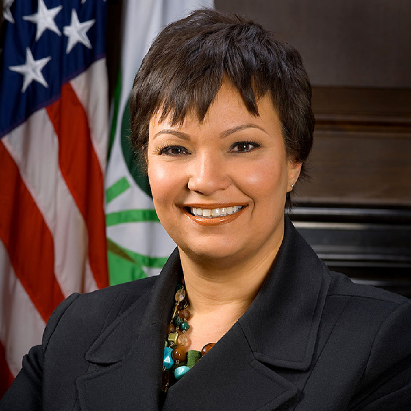 Lisa P. Jackson smiling at the camera with an American flag behind her.