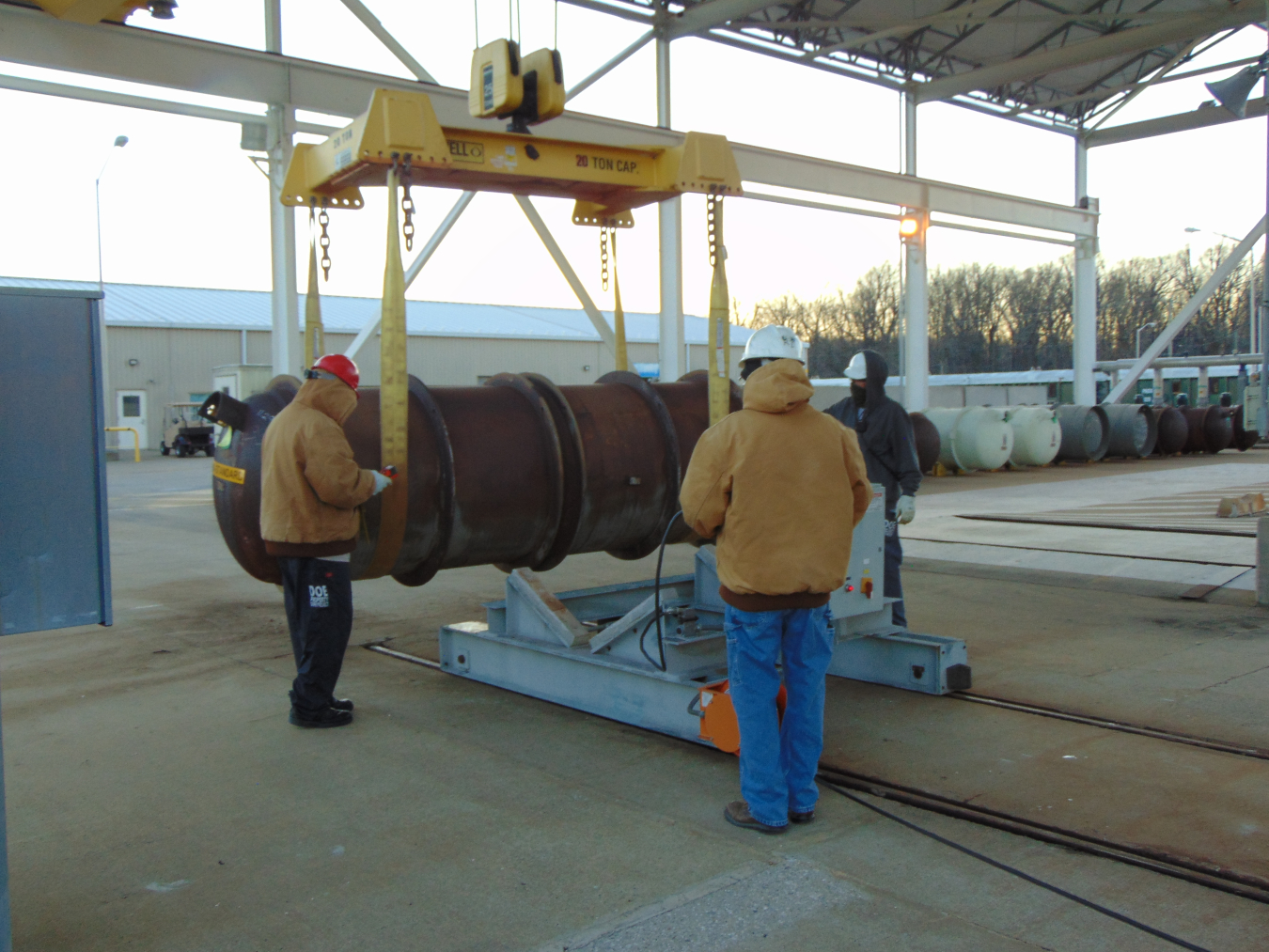 From left, Jim Johnson, Richard Darnall and Mike Price of Mid-America Conversion Services load a feed cylinder onto a transfer cart outside the depleted uranium hexafluoride (DUF6) conversion building at the Paducah Site.