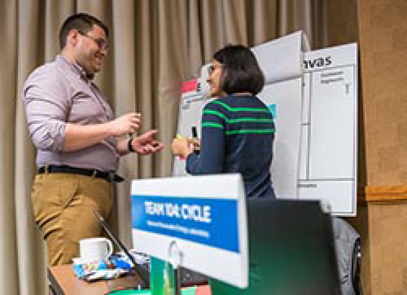 A man and a woman talking in front of a whiteboard. 