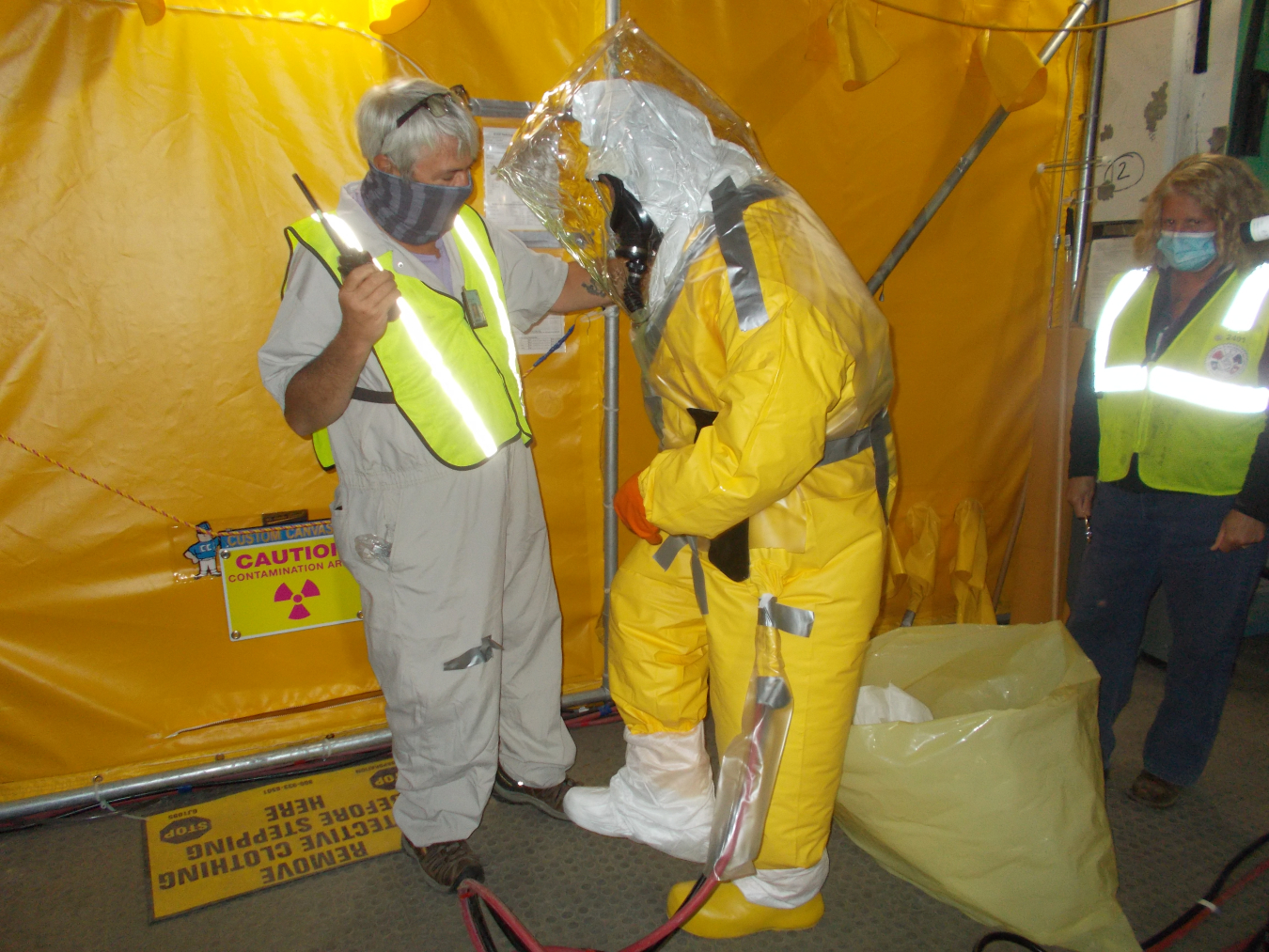A worker gets trained on how to get suited up for Product Purification Cell-South decontamination work.