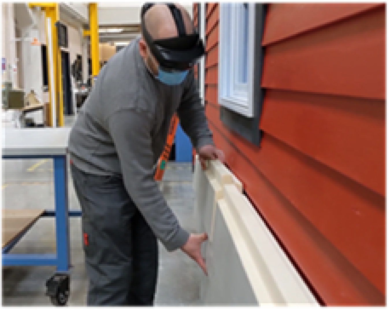 A man wearing a mask and working on panels on the side of a house.