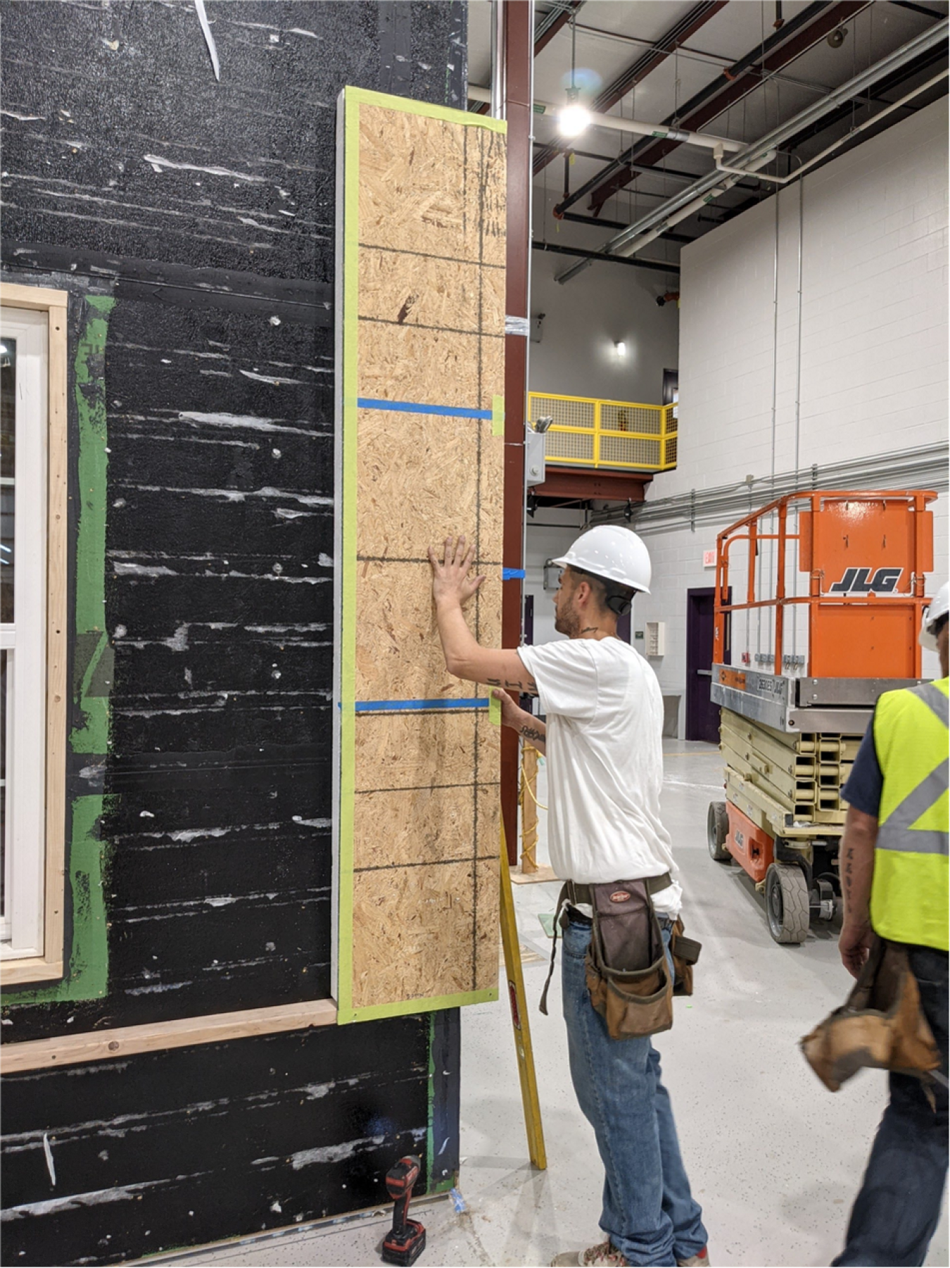 Men working in a warehouse with structurally insulated panels (SIPs).