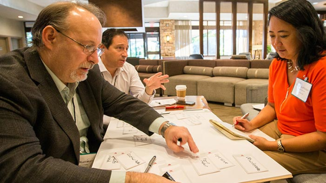 Three people looking at a large piece of paper.