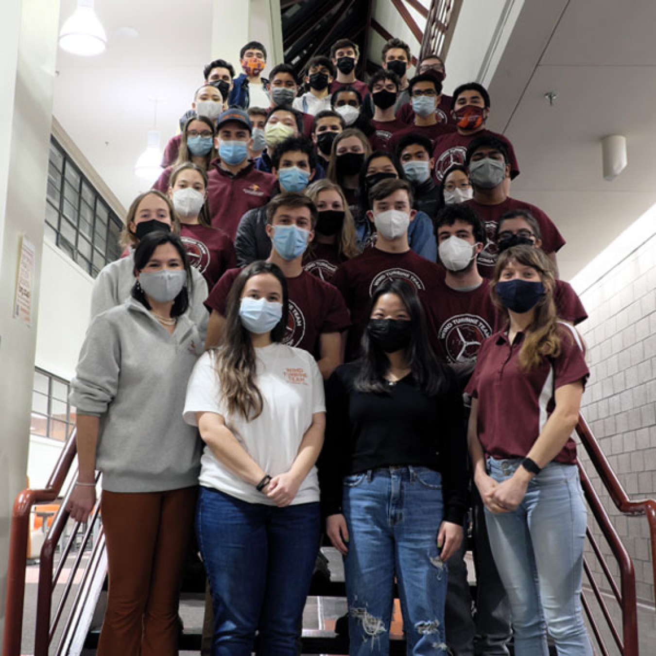 Students in masks standing on a staircase.