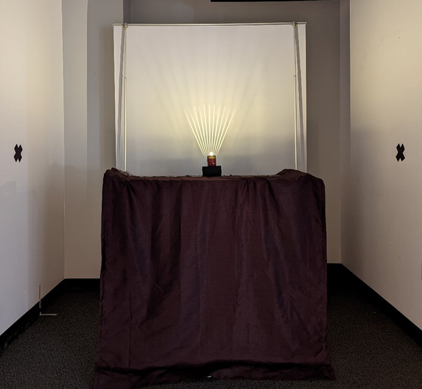 A test setup with a light shining on a rotating wand against a white screen.