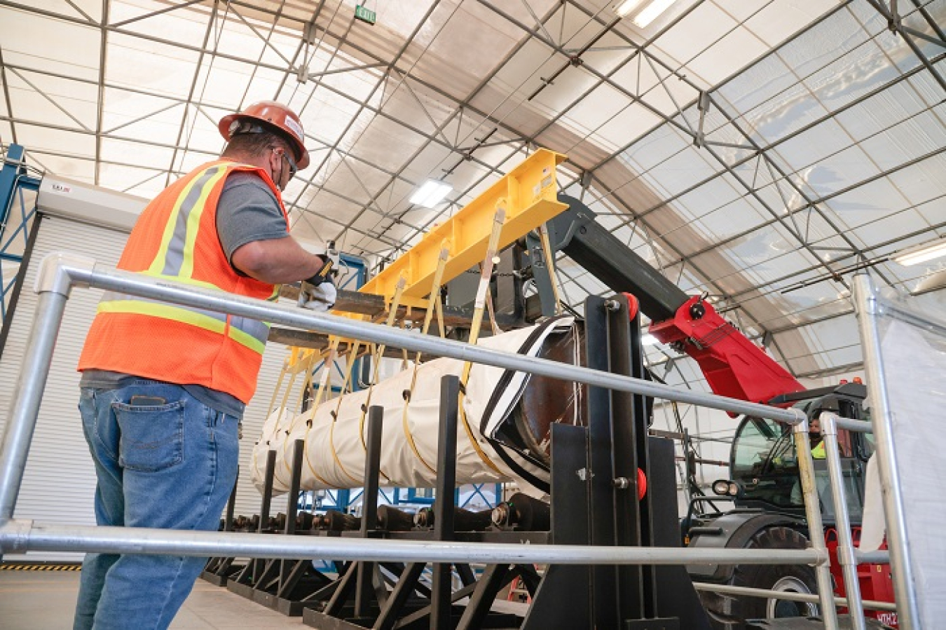 Newport News Nuclear BWXT-Los Alamos Waste Retrieval Operations Supervisor Juan Garcia guides a mock-up pipe, filled with cement that does not contain radioactive waste, while it is loaded onto a pipe-roller conveyor belt before being cut into sections. 