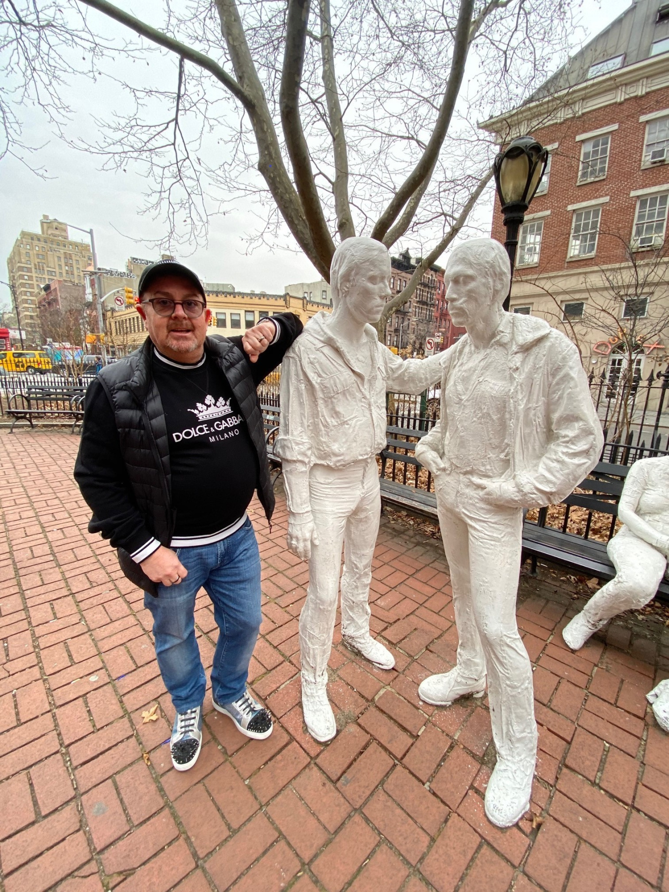 Paul Seymour at the Stonewall Inn in New York City, next to two white sculptures of people.