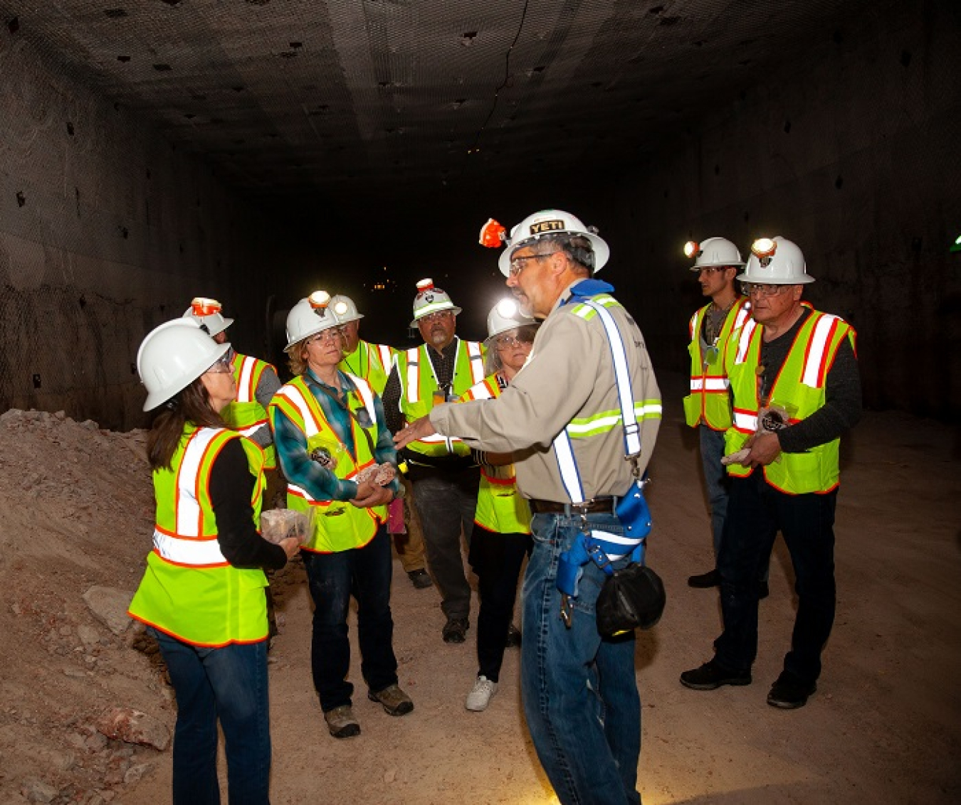 Waste Isolation Pilot Plant (WIPP) chief operating officer Mark Pearcy helps members of the National Governors Association Federal Facilities Task Force pick out souvenir salt 2,150 feet underground in newly created Panel 8 at WIPP.
