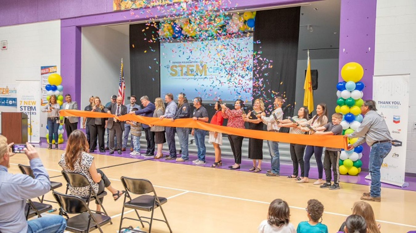 Representatives of Carlsbad Municipal Schools, Nuclear Waste Partnership and energy companies cut the ribbon and pop confetti in the gymnasium at Desert Willow Elementary School in Carlsbad, New Mexico, for a STEM Center grand opening.