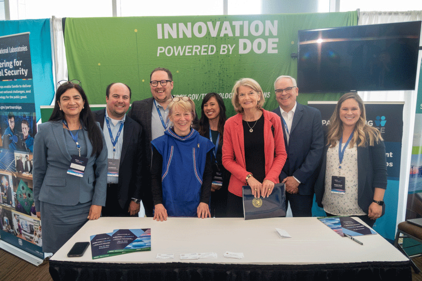 A group of people standing behind a booth at a conference.