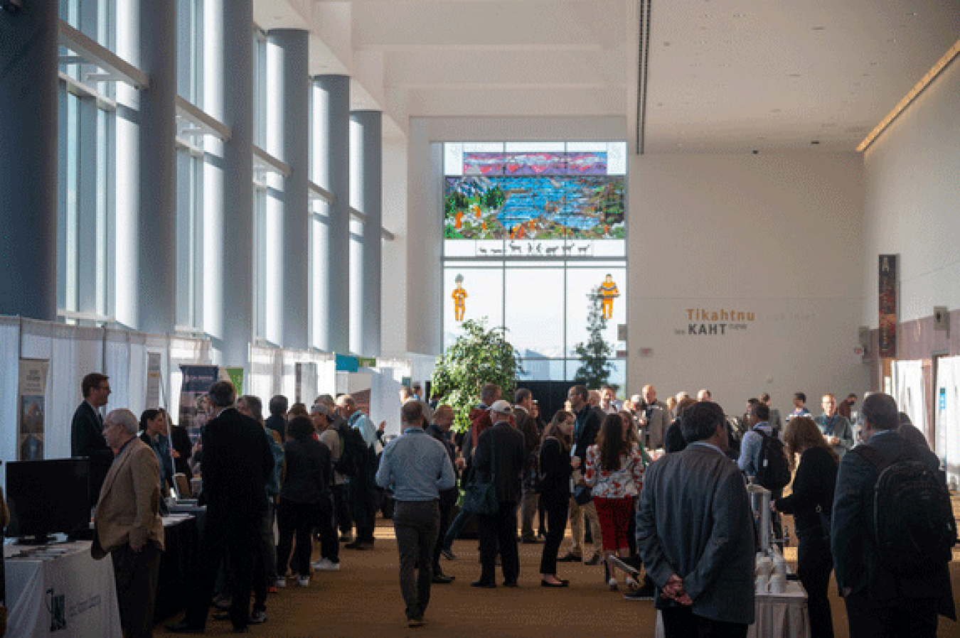 Attendees walking by different booths in a conference hall.