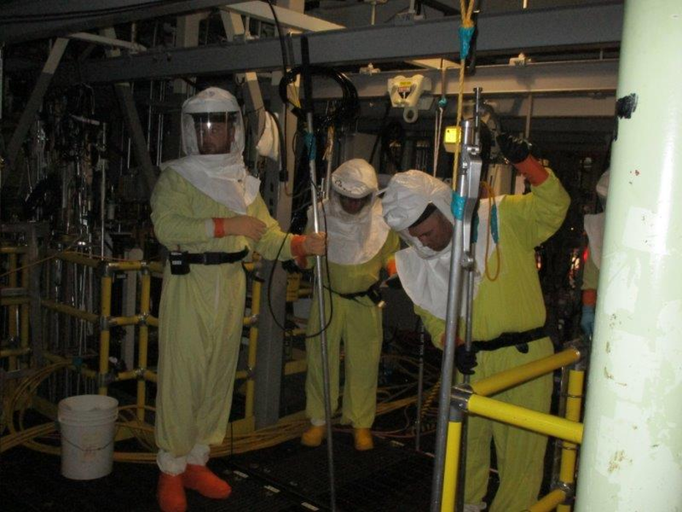 Workers with EM contractor Central Plateau Cleanup Company stand on grates above 16 feet of water, using long-handled tools to move debris from the floor of the 1.2 million-gallon K West Reactor Basin into underwater bins. 