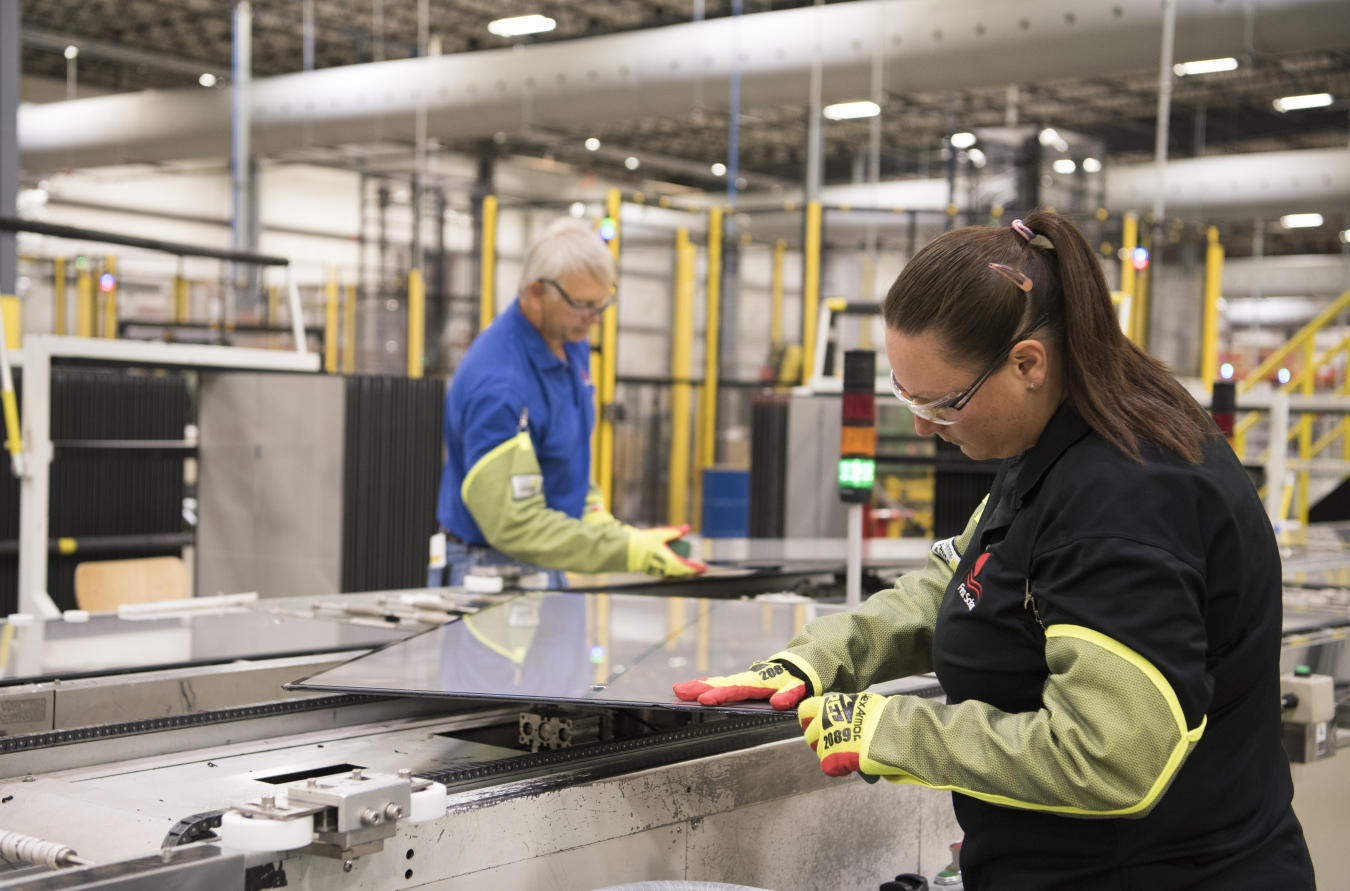 A woman builds a solar panel in a manufacturing solar plant.