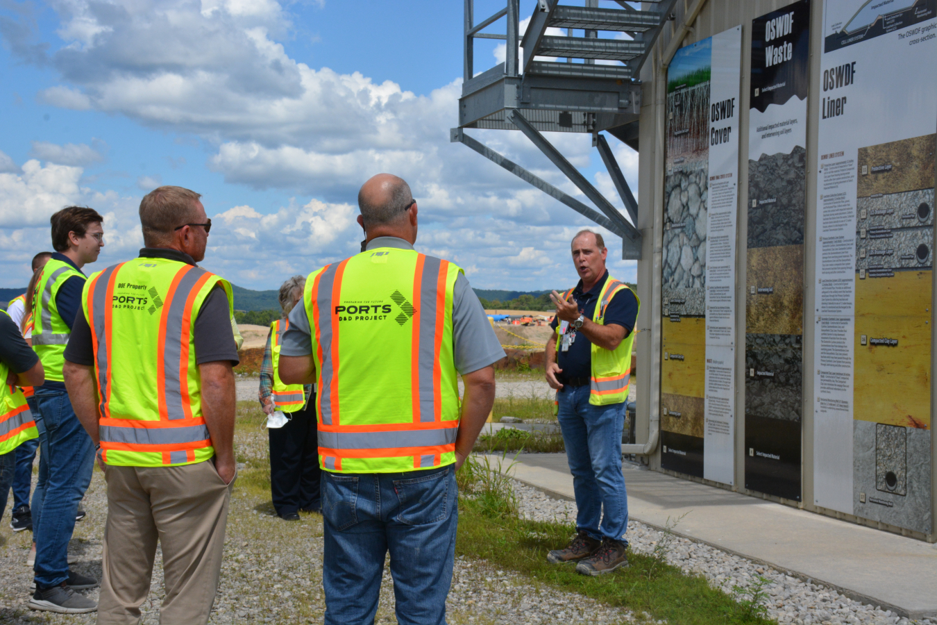 Frank Miller, far right, Fluor-BWXT Portsmouth director of disposal integration, discusses the engineered design of the Portsmouth Site’s On-Site Waste Disposal Facility in front of a cross-section rendering detailing 17 different layers of natural and man-made materials working together to ensure environmental protection for 1,000 years.