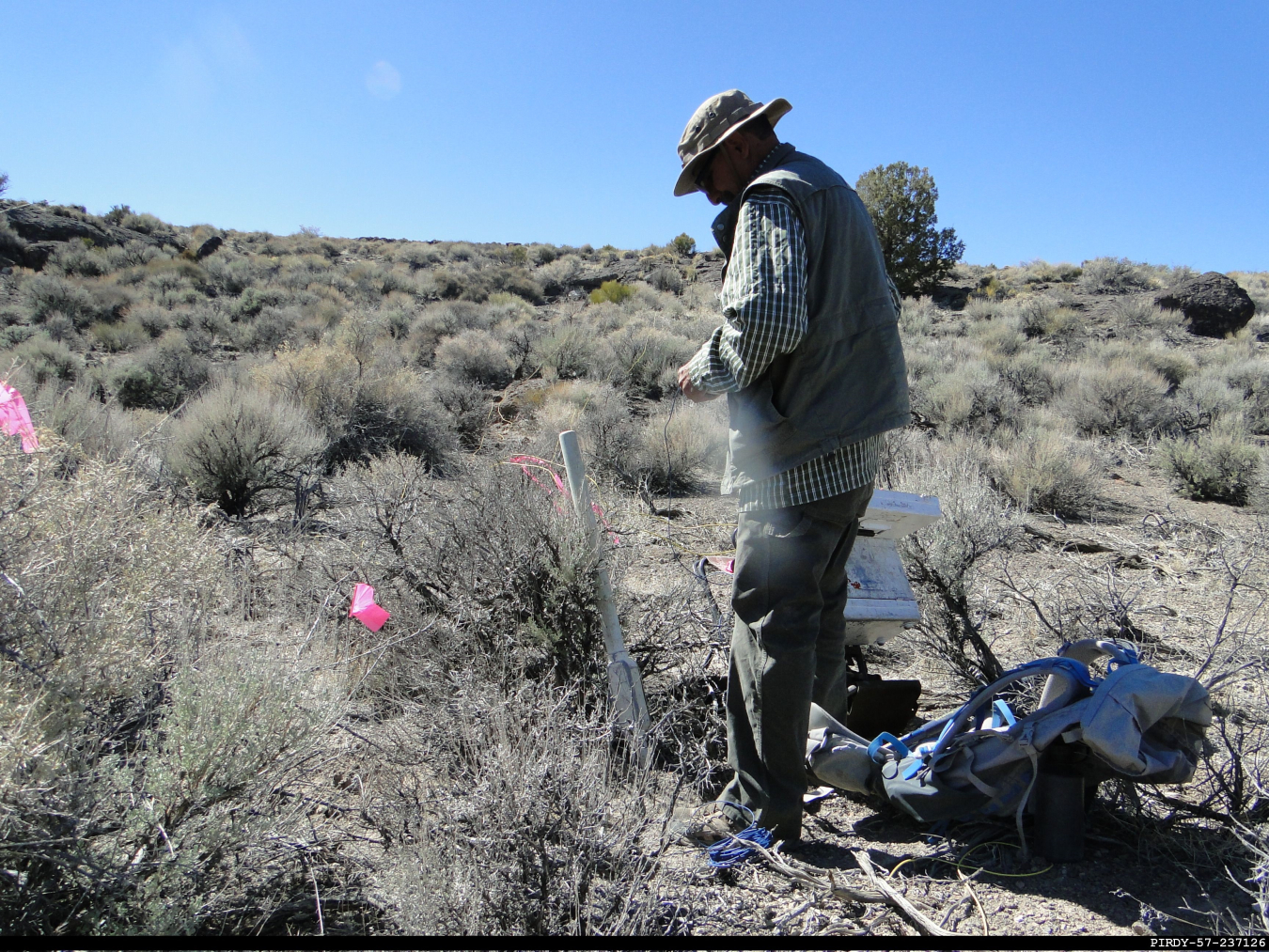 An EM Nevada Program worker arrives at a location marked by a pink flag to set up a receiver apparatus as part of a geophysical survey. EM Nevada collected electrical data from this fixed point and compiled the information to help provide a picture of the underground. 